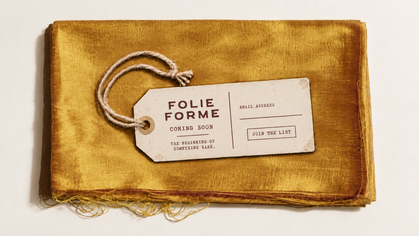 Folie Forme luggage tag resting on vintage marigold fabric